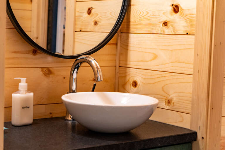Refresh in your stylish bathroom, featuring a modern vessel sink and natural wood paneling that brings warmth to every moment.