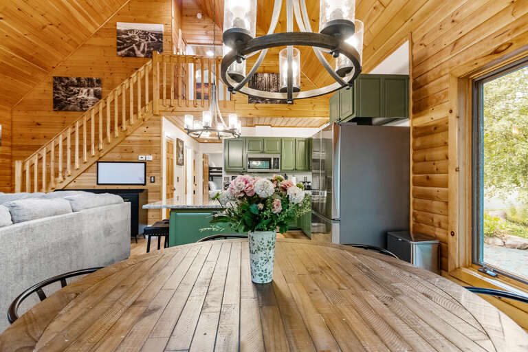 Warm wood beams and vaulted ceilings create an inviting, airy atmosphere in this open-concept cabin, where your living, dining, and kitchen spaces flow seamlessly together—perfect for gathering and unwinding.