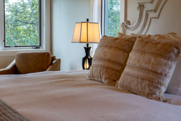 Sink into this inviting bed with its plush linens and elegant headboard, while soft lamp light creates the perfect ambiance for your stay. Your peaceful garden view awaits.