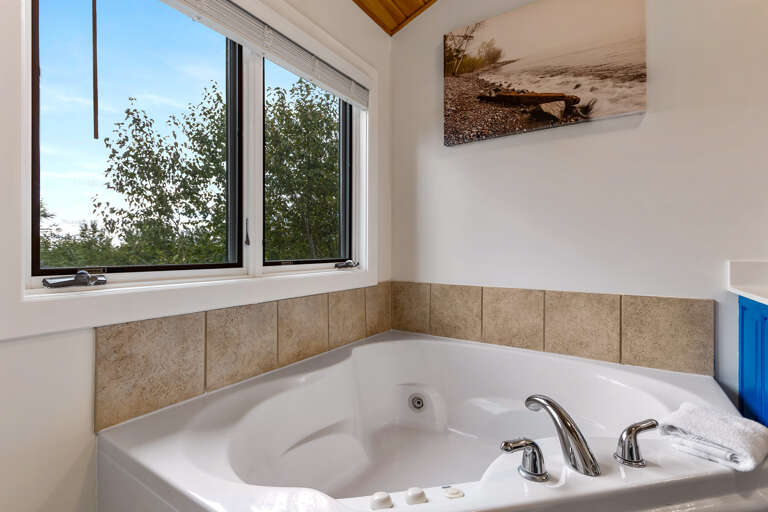 Sink into this inviting soaking tub and let the day melt away. Natural light streams through the window, and calming lake-inspired artwork sets the mood for pure relaxation.