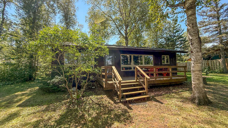 This charming woodland cabin is surrounded by towering trees, offering a serene, nature-immersed setting. The private deck invites you to relax outdoors in peaceful seclusion, perfect for unwinding after a day of exploration.
