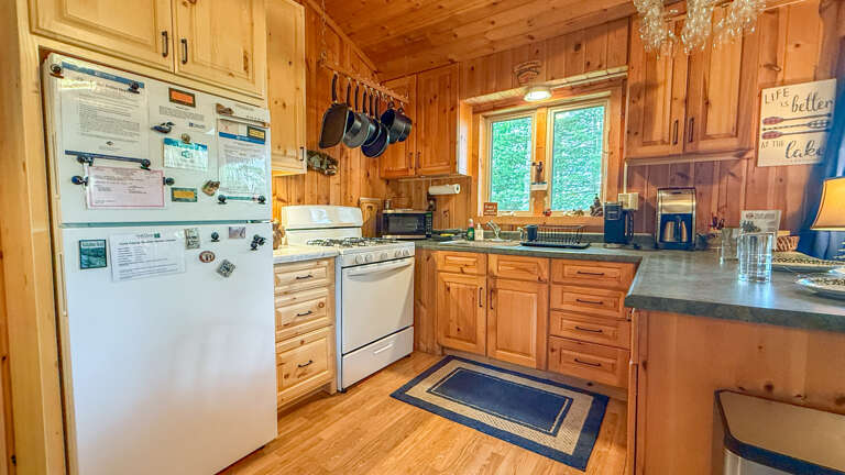 Gather around this fully-equipped kitchen with warm wood cabinetry, granite counters, and natural light pouring through the windowsâyour perfect lakeside retreat for home-cooked meals.