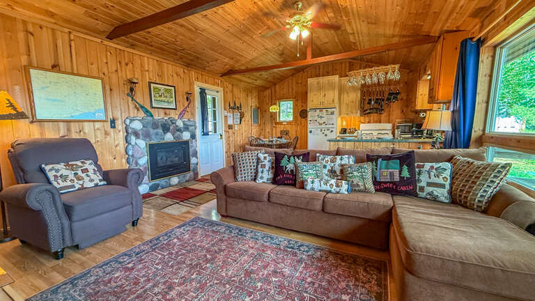 Sink into the cozy charm of this open-plan living space, where exposed beams, warm wood, and a stone fireplace invite you to unwind after a day of adventure.