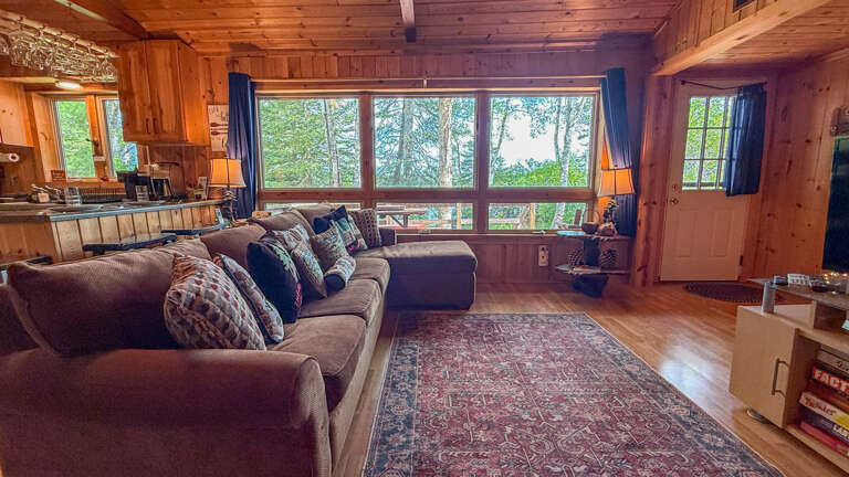 Sink into plush seating surrounded by warm wood and natural light streaming through large windows overlooking tranquil greeneryâyour perfect retreat for unwinding after a day of adventure.