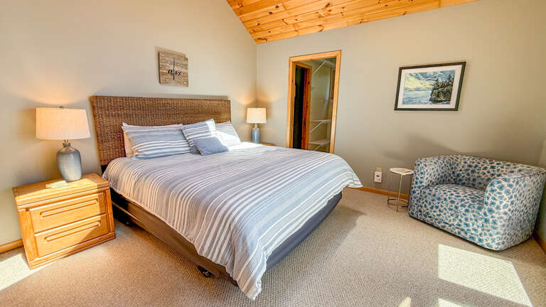 Settle into your serene bedroom retreat with a plush bed, vaulted wood ceiling, and cozy seating that invites you to unwind after a day exploring.