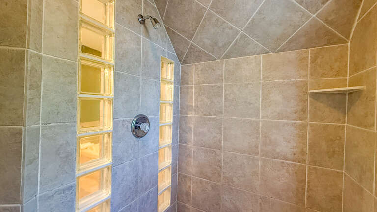 Step into your private spa-like shower with elegant glass block accents and spacious tiled walls that create a serene, light-filled retreat perfect for unwinding after exploring.