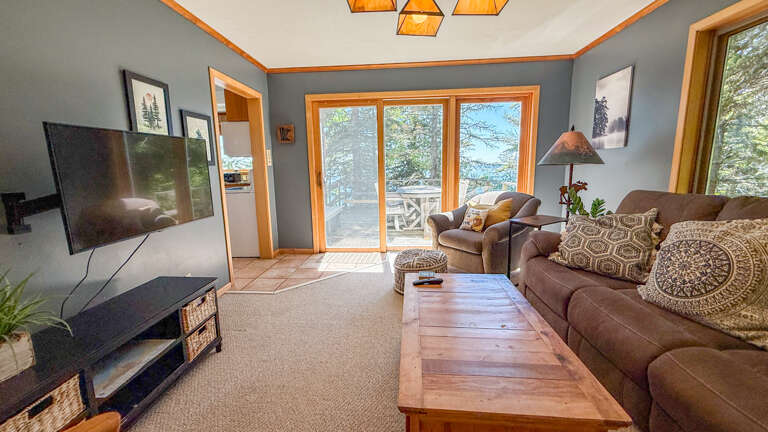 Unwind in your cozy living room with plush seating, a flat-screen TV, and stunning lake views through the glass doorsâyour perfect retreat awaits.