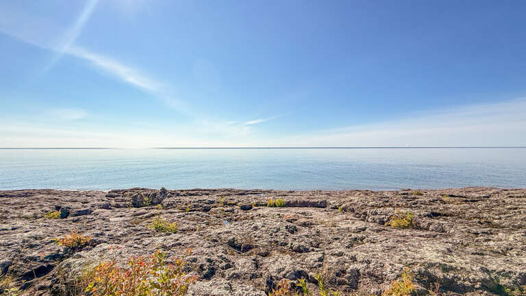 A serene waterfront setting where rugged shoreline meets endless sky. Perfect for peaceful getaways and soaking in the natural beauty of the surrounding landscape.