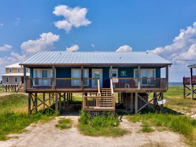 Stilt Beach House With Blue Roof Under Sunny Sky Stilt Beach House With Blue Roof Under Sunny Sky