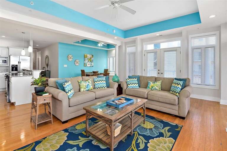 Bright-blue-living-space, Beige-sofas, Bold-rugs, Breezy-windows