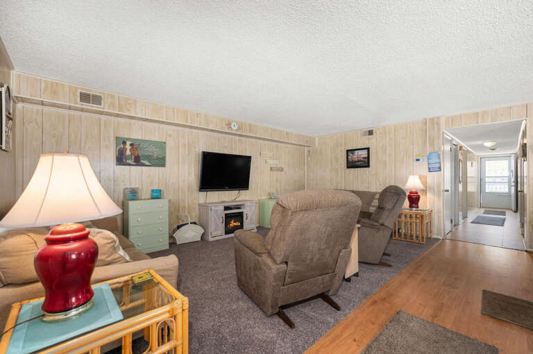 Living Room Laid With Laminate, Lit By Lamps, Leading To Lighted Hallway