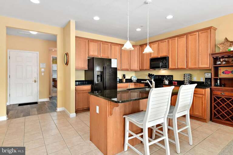 Kitchen With Wooden Cabinets And White Bar Stools