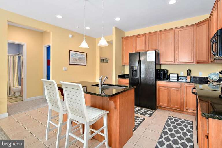 Bright Kitchen With Wooden Cabinets And Breakfast Bar In Vacation Rental