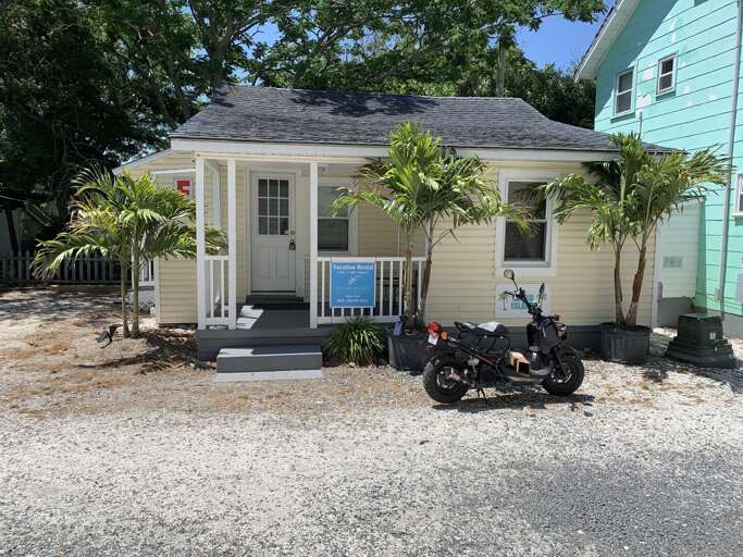 Small Bungalow Beside Bike, Bright Blue Door, Under Sunlight