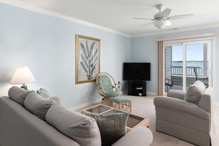 Vacation Rental Living Room With Soothing Sea Views And Soft-hued Sofa Setup, Leading To A Balcony
