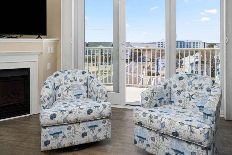 Sea-themed Seating Space With Sliding Glass Doors, Fireplace, And Distant Buildings