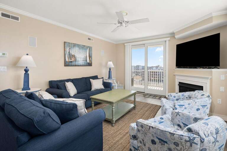Beachfront Living Room With Balcony Access Showcasing Sofas, Chairs, And Television