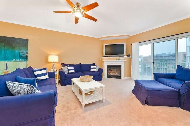 Spacious Room With Blue Sofas, Beige Walls, Fireplace, And Sea Artwork