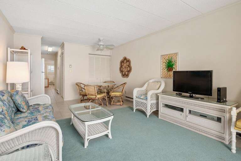 Pastel-colored Living Space With Woven White Furnishings And A Flat-screen TV