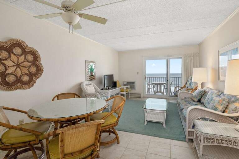 Bright Beachfront Living Room Leading To Balcony, With Dining Table And Tropical-themed Furnishings