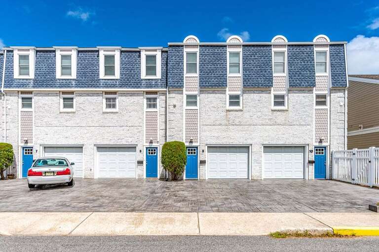 Row Of Residential Units With Blue Roofs And Multiple Garage Doors