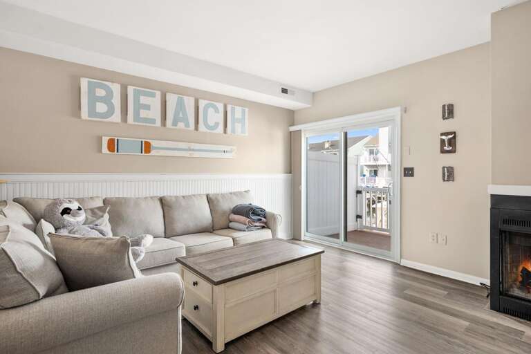 Beige Beach-themed Living Space With Sliding Balcony Doors, Fireplace, And Sofa