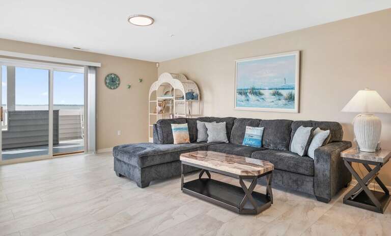 Living Room With Plush Sofa, Sleek Shelves, And Seaside Scenery Seen Through Sliding Door