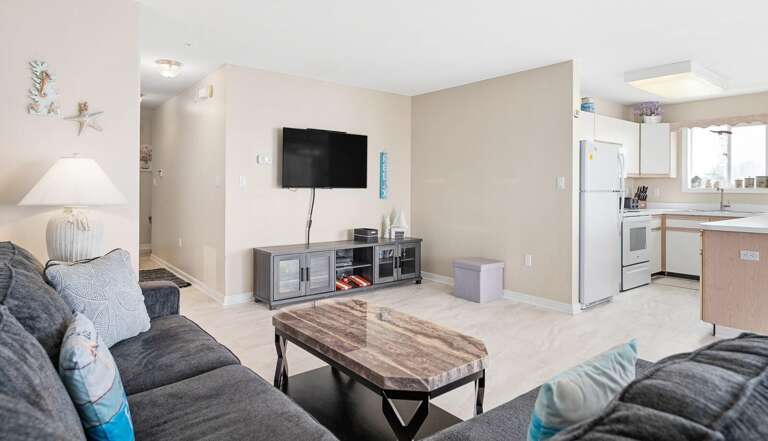 Bright, Breezy Living Space With Large Couch, Flat-screen TV, And Open Kitchen In Vacation Rental
