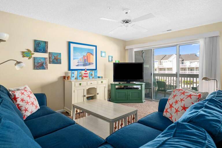 Living Room With Blue Sofa, Balcony Access, Marine Motifs, And Mounted TV