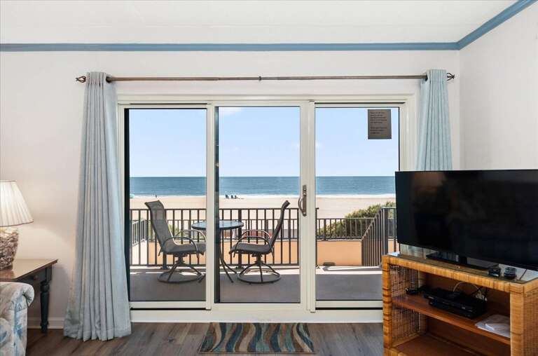 Room With Sliding Glass Doors Leading To Beach Balcony, Two Chairs Facing The Sea, Television In Foreground