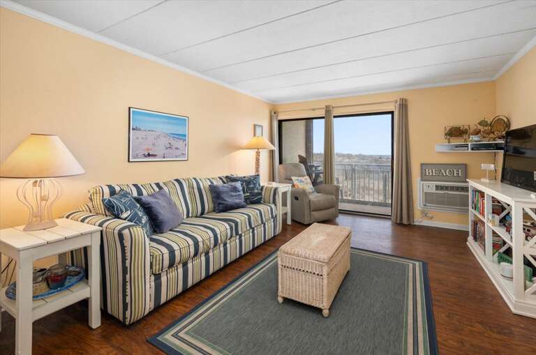 Seaside Vacation Rental Living Room With Striped Sofa And Sliding Door Leading To Balcony