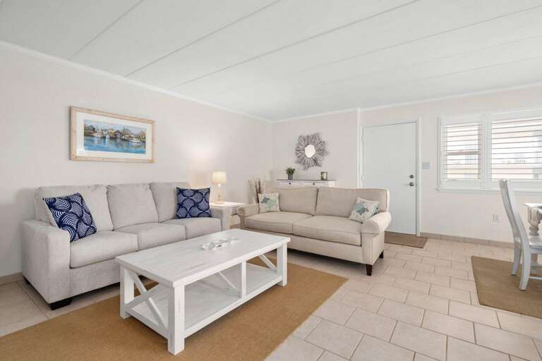 Bright, Beachy Living Area In A Vacation Rental With White Sofas And Tiled Floor