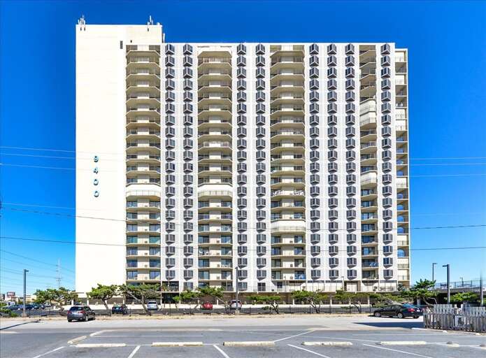 High-rise Building Beside Broad Boulevard Under Bright Blue Sky