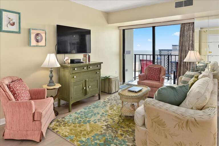 Living Room With Floral Rug, Pastel Chairs, And Balcony Doors