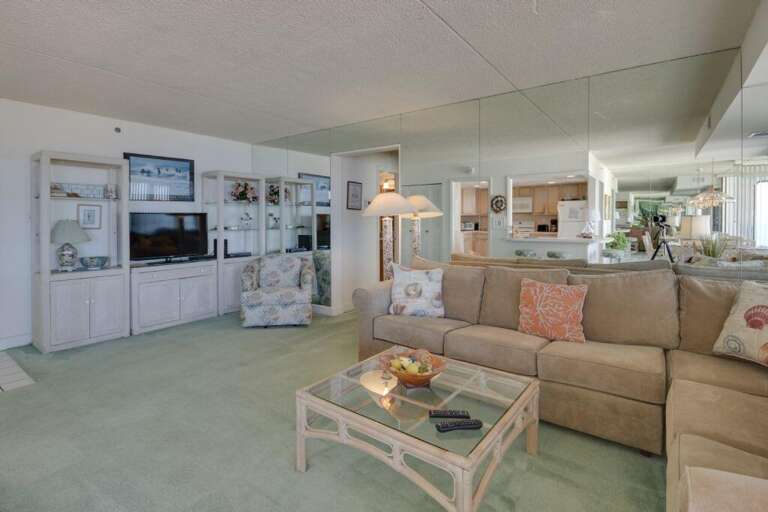 Light-filled Living Space With Plush Sofas And Pastel Pillows, Flowing Into A Kitchen Area
