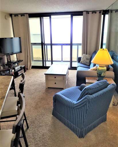 Brightly Lit Living Area Leading To A Balcony In A Vacation Rental