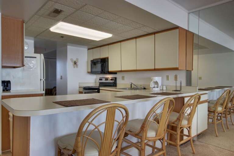 Spacious Kitchen Setting With Sleek Surfaces And Wooden Chairs