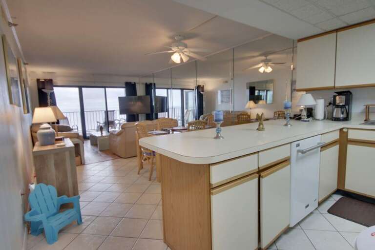 Spacious Indoor Scene With A Kitchen Leading To A Living Area, Light Tones Throughout