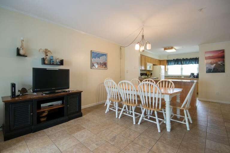 Spacious Living Area With Dining Table, Chairs, And TV