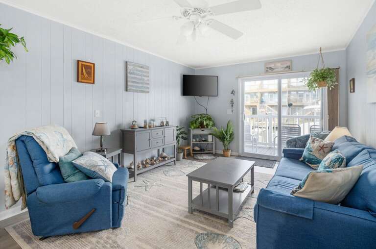 Light-filled Living Space With Blue Sofas And Breezy Balcony Access, Ideal For A Vacation Rental