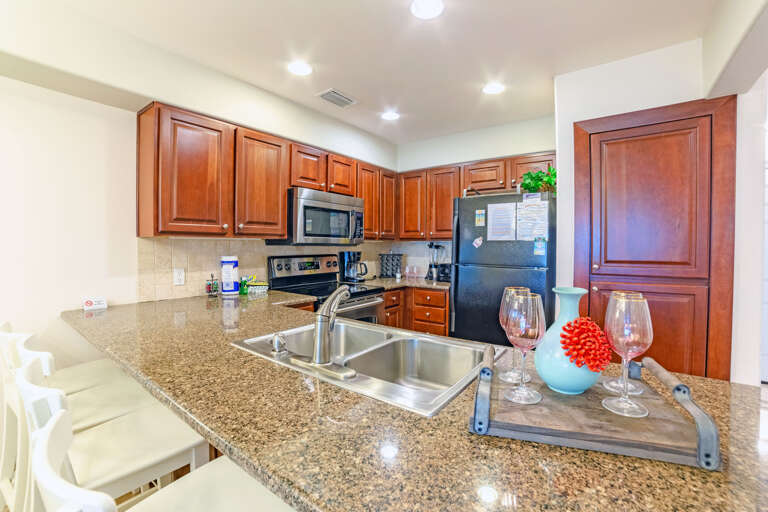 Spacious Kitchen Area In Vacation Rental With Sleek Surfaces And Wooden Cabinets