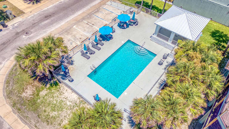 Vacation Rental View Of A Vibrant Pool, Palm Trees, And Pavement