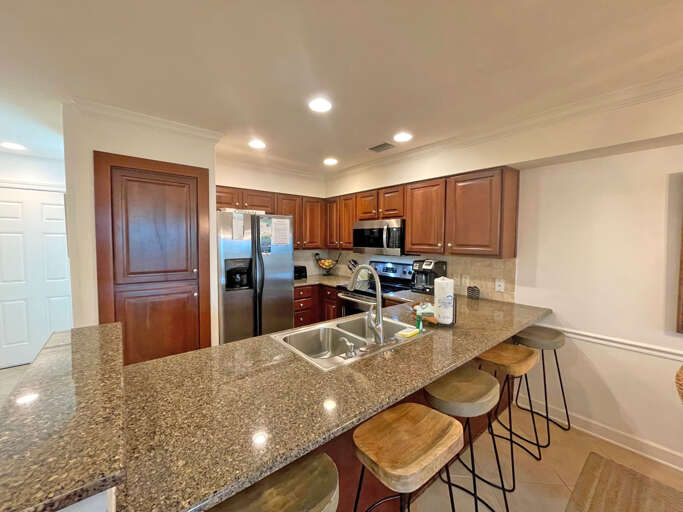 Spacious Kitchen With Stools And Stainless Steel Appliances In A Vacation Rental