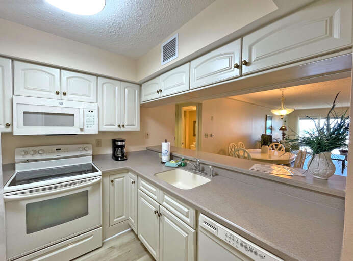 Bright, White Kitchen Leading To Luminous Living Area In Spacious Vacation Rental