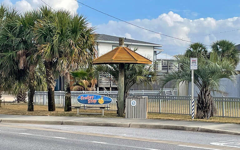 Street View Of A Fenced Property With A Sign, Palms, And A Gazebo