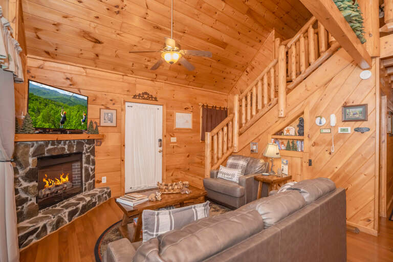 Wood-paneled Living Space With Fireplace, Television, Sofa, And Staircase