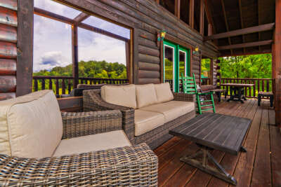 Wooden Deck With Wicker Sofa And Table Overlooking Lush Landscape