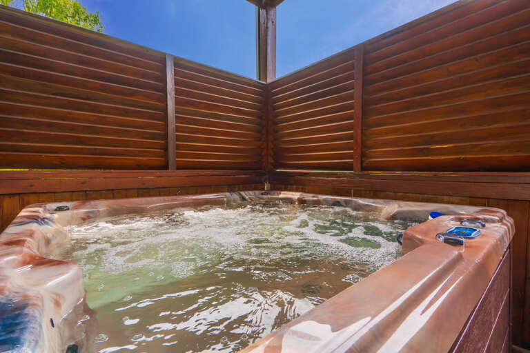 Outdoor Bubbling Brown Bathtub Bordered By High Wooden Walls Under Sunny Skies