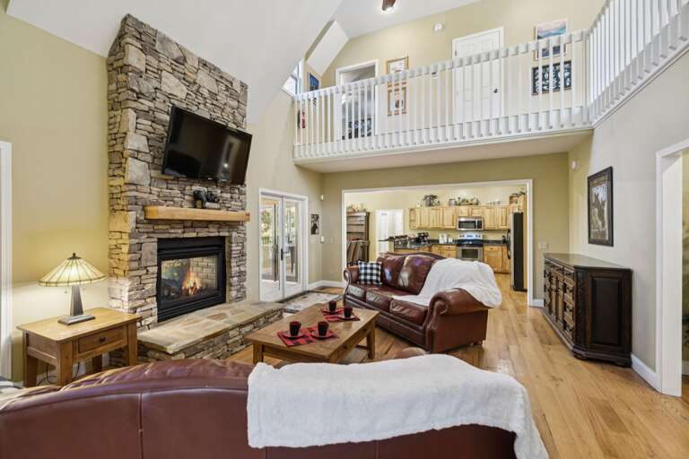 Spacious Living Room With Stone Fireplace, Leather Sofas, And Upper-level Balcony In Vacation Rental