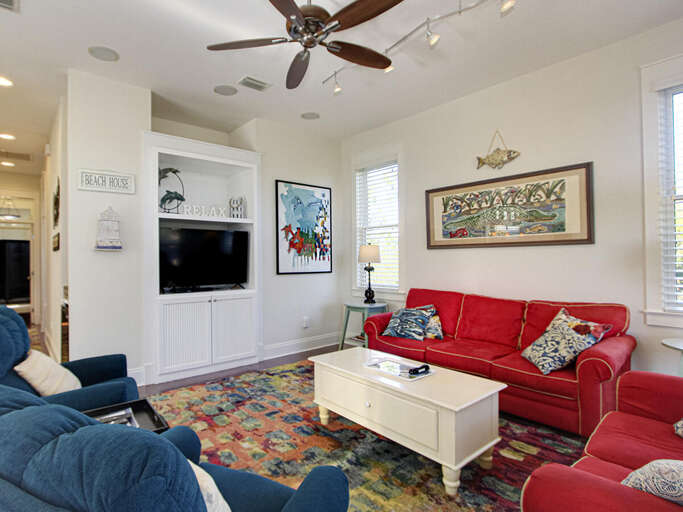 Bright Living Room With Red Sofas, Colorful Rug, And Large TV